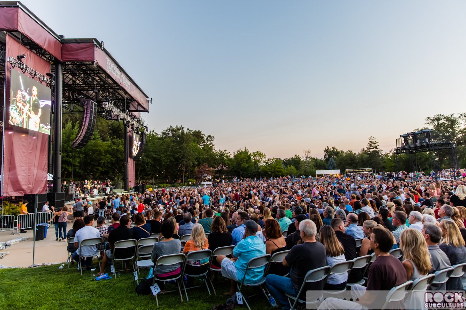 Musicians performing on the Ironstone Amphitheatre stage with a large outdoor audience