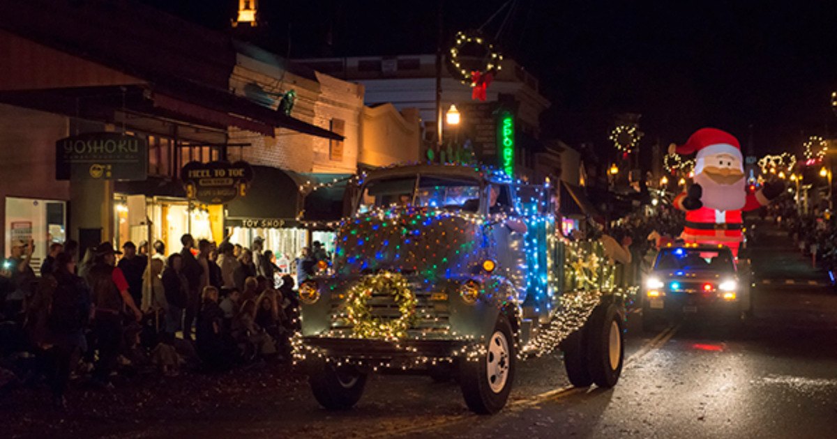 An illuminated truck passing decorated downtown Sonora storefronts during the Christmas Parade